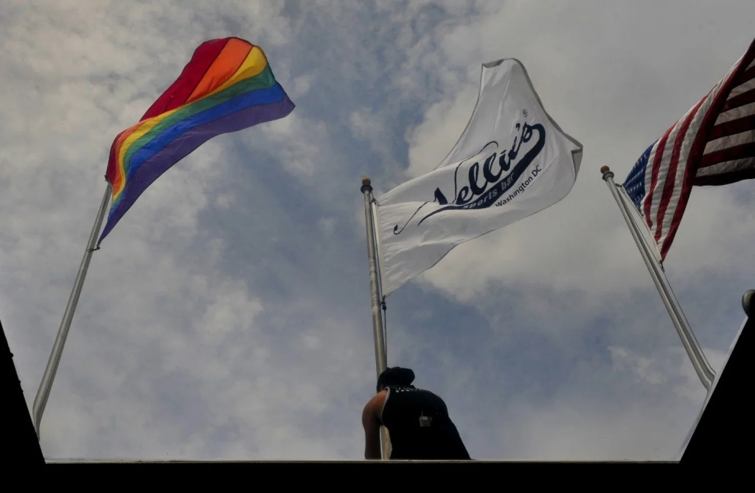 At Nellie’s Sports Bar, Drew Hilton raises three flags on the roof as the bar opened early on Friday to celebrate the Supreme Court’s decision. (Michael S. Williamson/The Washington Post)